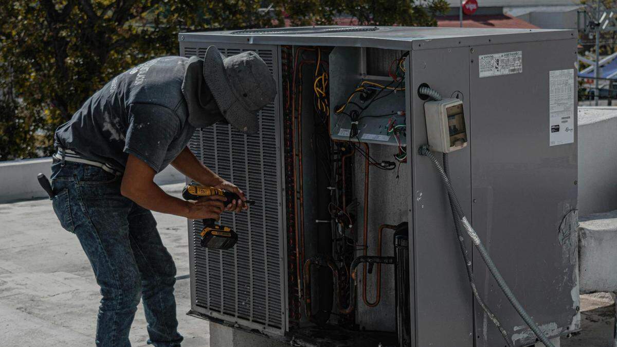 Handyman working on a HVAC system’s outside unit, the conditioner.