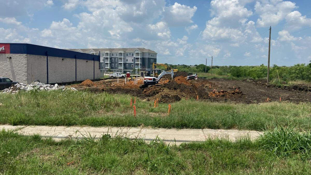 A backhoe turns dirt.