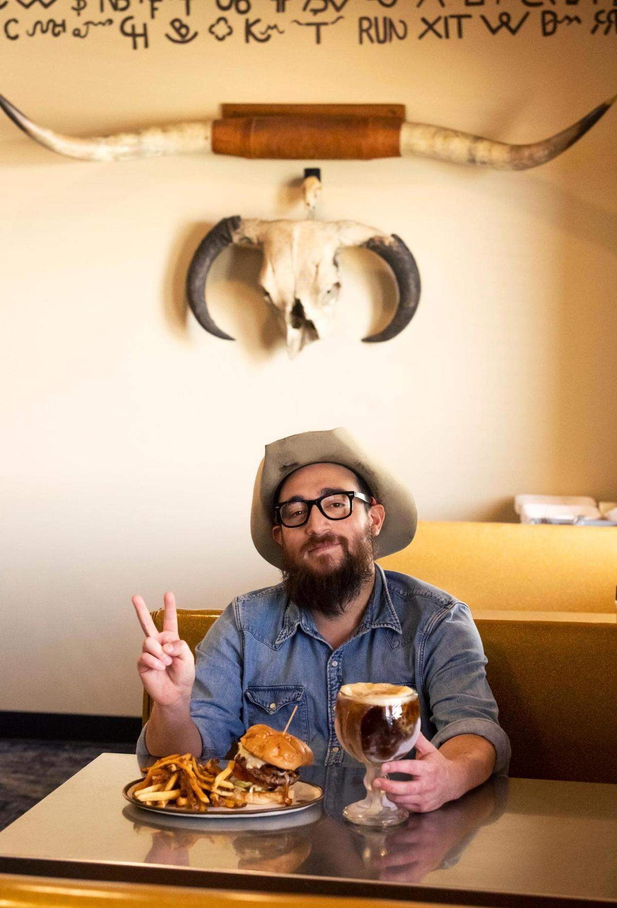 Fred’s Texas Cafe executive chef Fabian Alvarado poses with the Diablo burger on Friday, June 17, 2022. The Diablo burger, one of Fred’s iconic menu items, features chipotle brown butter, grilled onions, Swiss cheese, pickles, lettuce, tomato and mustard.