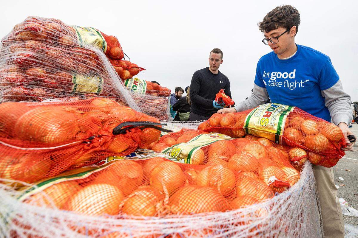 Igor Colombelli lifts a bag of onions to prepare for sorting into bags during the 4th annual Thanksgiving Mobile food distribution at AT&T Stadium in Arlington on Friday, November 17, 2023.