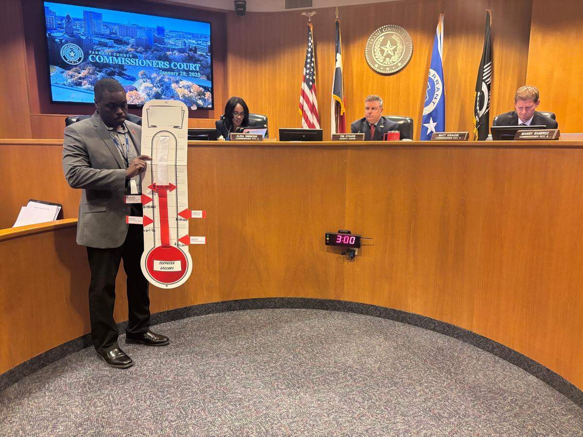 Gerald Hodges, a staffer in Precinct 2 Commissioner Alisa Simmons’ office, holds a display showing how much the county has spent to date on outside counsel in the case brought by the family of Anthony Johnson Jr. on Jan. 28, 2025. Johnson died after an altercation with guards in the Tarrant County jail in April 2024, and the medical examiner ruled his death a homicide.
