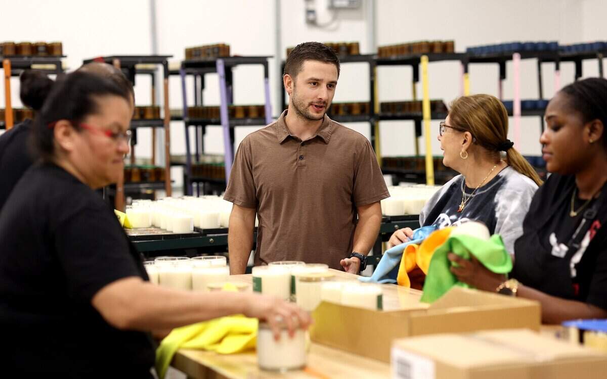 Jacob Johnson, owner of Calyan Candles, talks to employees as they wipe down and box candles at the production facility on Friday, Sept. 12, 2025, in Arlington.