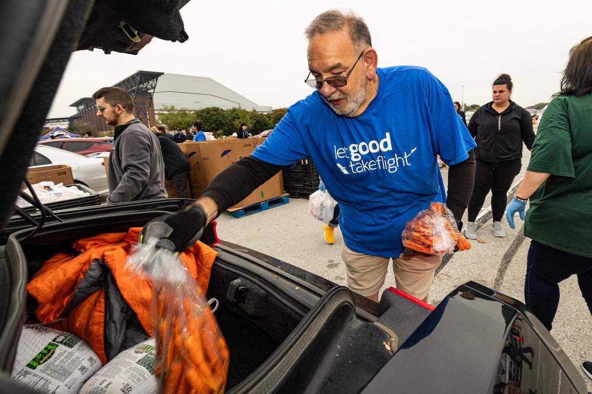 Orlando Velazquez puts various Thanksgiving groceries into the trunk of a car during the 4th annual Thanksgiving Mobile food distribution at AT&T Stadium in Arlington on Friday, November 17, 2023.