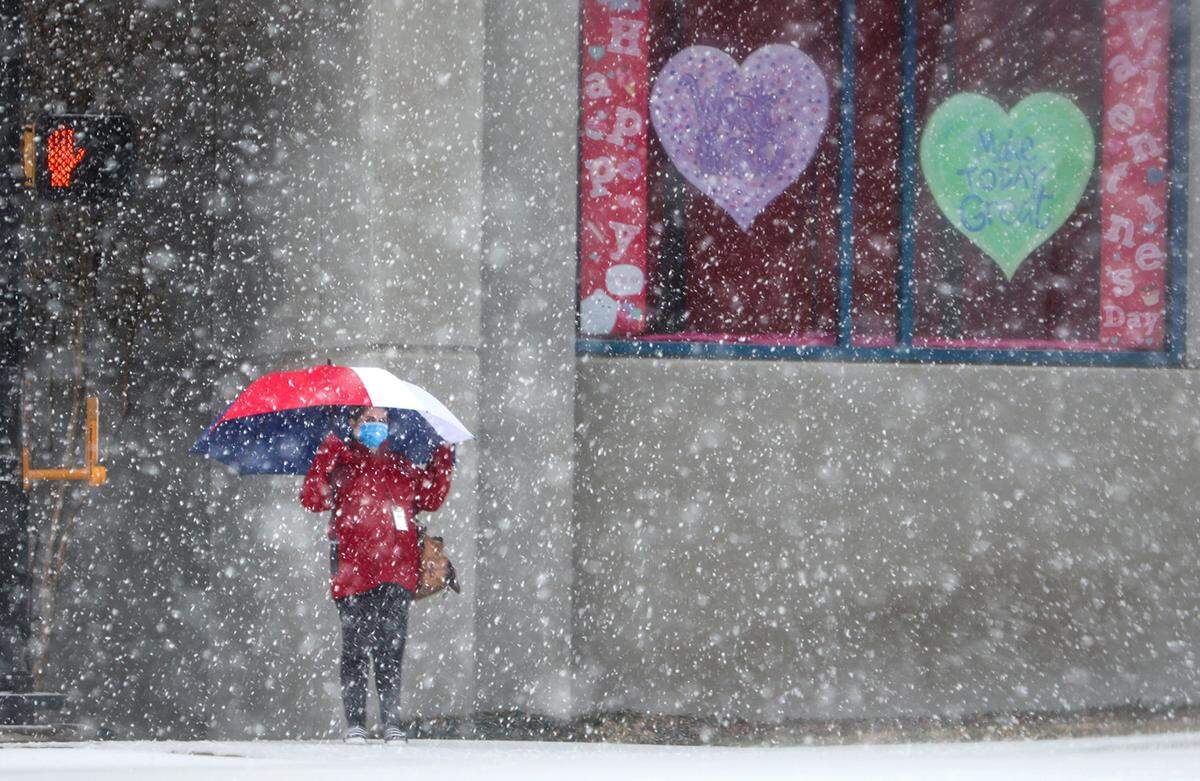 A woman waits to cross Rosedale Street as snow falls on Thursday, February 3, 2022, in Fort Worth.