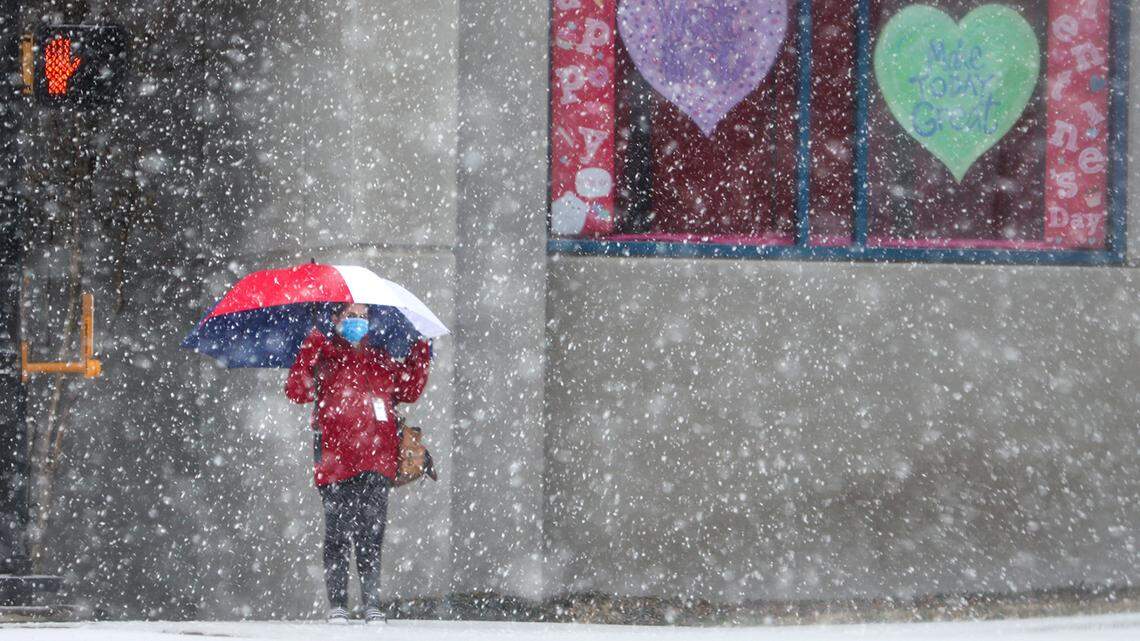 A woman waits to cross Rosedale Street as snow falls on Thursday, February 3, 2022, in Fort Worth.