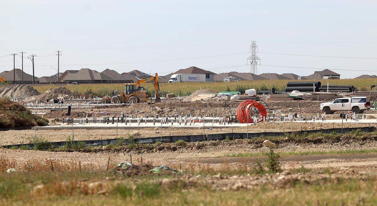 A housing development under construction in an open field with a windmill in the background.