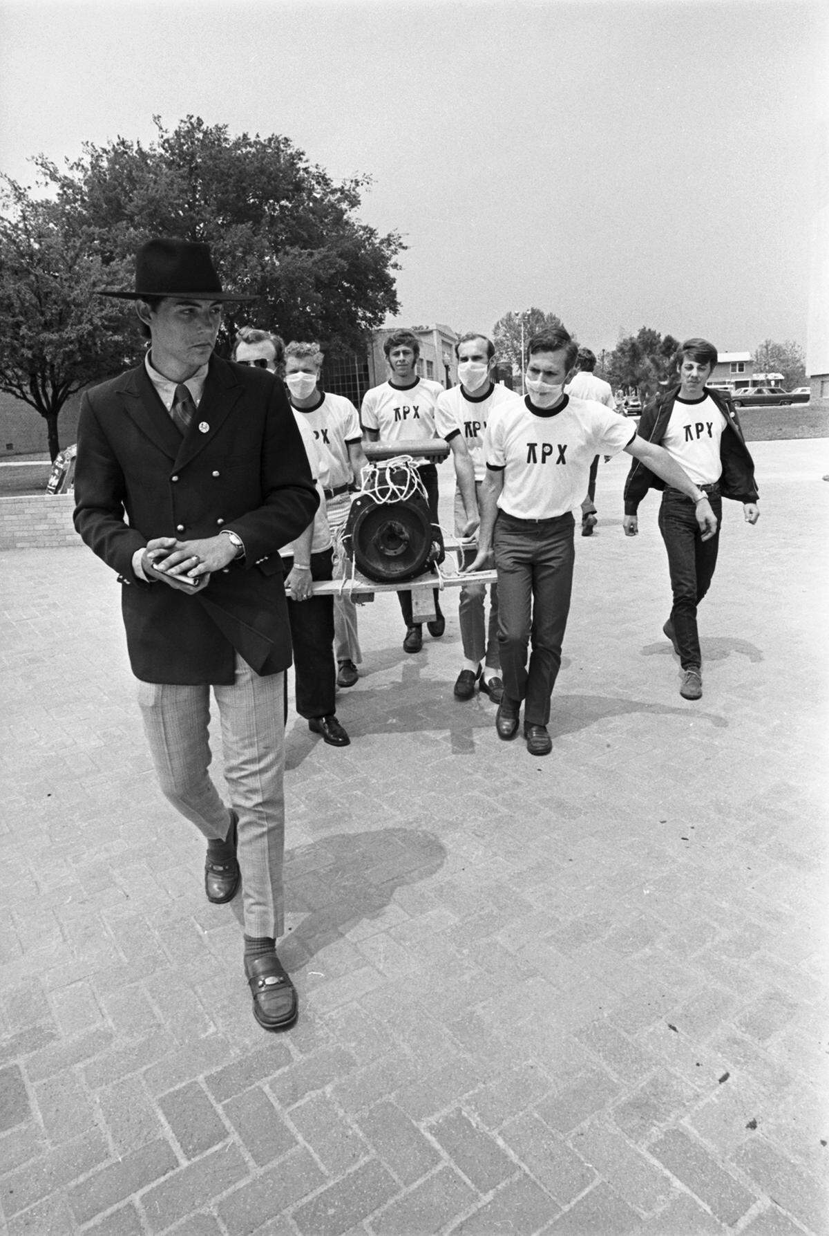 April 22, 1970: Students at the University of Texas at Arlington are seen carrying an internal combustion engine across campus to be buried in a shallow grave on campus for Earth Day. Alpha Rho Chi, the UTA architecture fraternity, led the “funeral services” and its pledges wore surgical and gas masks as the engine was lowered into its grave and a live oak tree was planted on top.