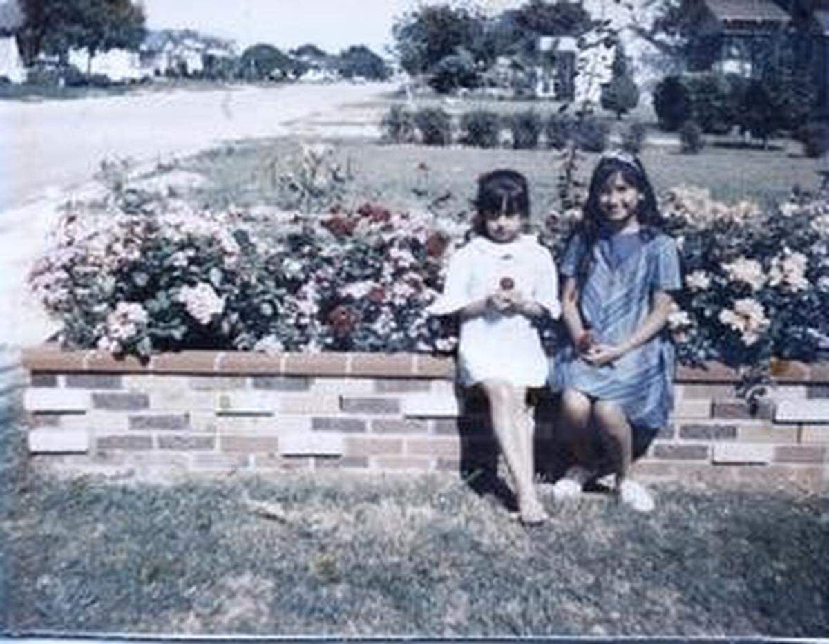 Anita Vasquez, 6, left, and her sister Rosemary Galdiano, 11, sit in front of their house on Drew Street in Worth Heights, 1966.