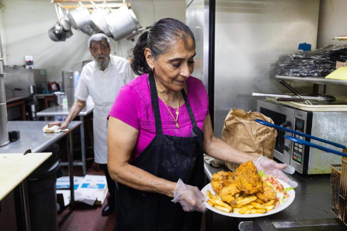 Maria Martinez preps a fried chicken plate as her father, Jesus Borja, watches at the Jesús Family Restaurant on Main Street in Fort Worth.