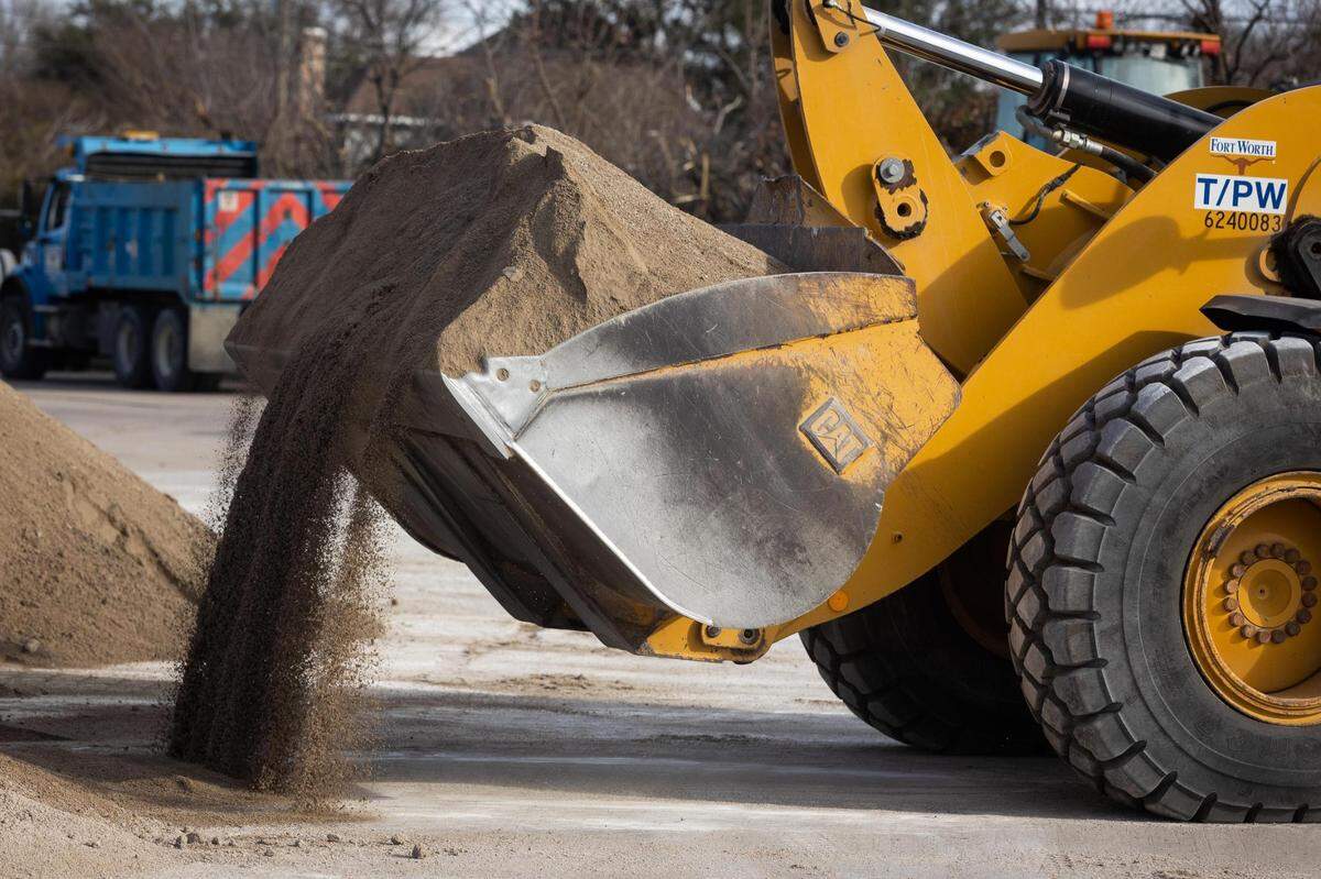 A tractor loads sand and salt mixture to sift as the city prepares for a winter storm Monday, Jan. 31, 2022, in Fort Worth.