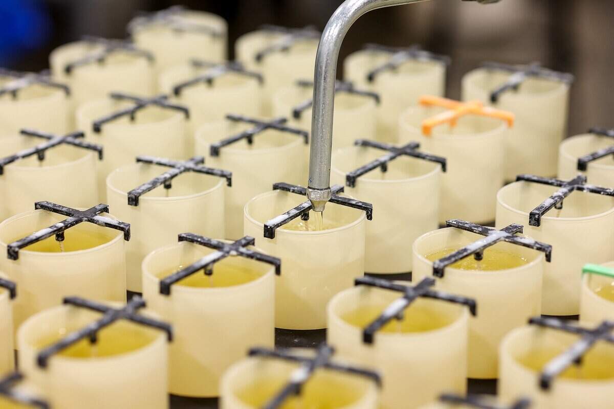 Yoshi Hughes, an apprentice machine operator, fills glass containers with hot wax while making candles at Calyan Candles on Friday, Sept. 12, 2025, in Arlington.