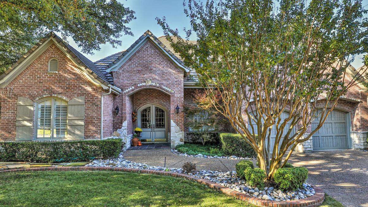 The home at 6732 Medinah Drive is surrounded by beautiful landscaping and shaded by flourishing trees.