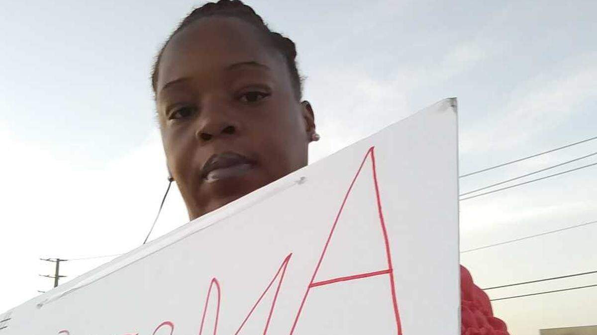 Akina Brodeak, college grad and mom, holds up signs on Lamar Street near Interstate 30 on Wednesday asking passers-by to take one of her resumes and hire her for meaningful employment