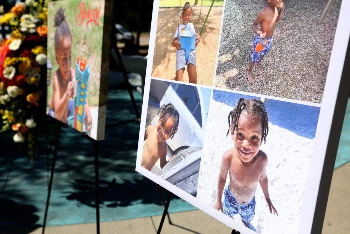 Photos of Bakari Williams, 3, stand beside the Don Misenhimer Park splash pad in Arlington during a press conference on Monday, October 3, 2021. Williams died last month from a brain-eating amoeba he most likely while encountered playing at the splash pad.