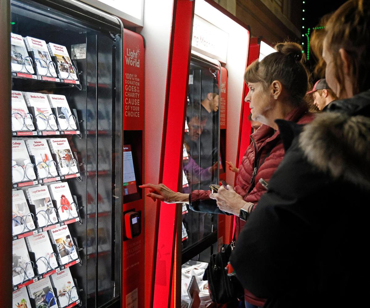 Melanie Lundeen makes her choice at the Giving Machine as daughter McKayla Parr looks on during Fort Worth’s lighting of the 77th Annual Fort Worth Community Christmas Tree in Sundance Square plaza. The machines offer a cashless way to give donations to nonprofits.
