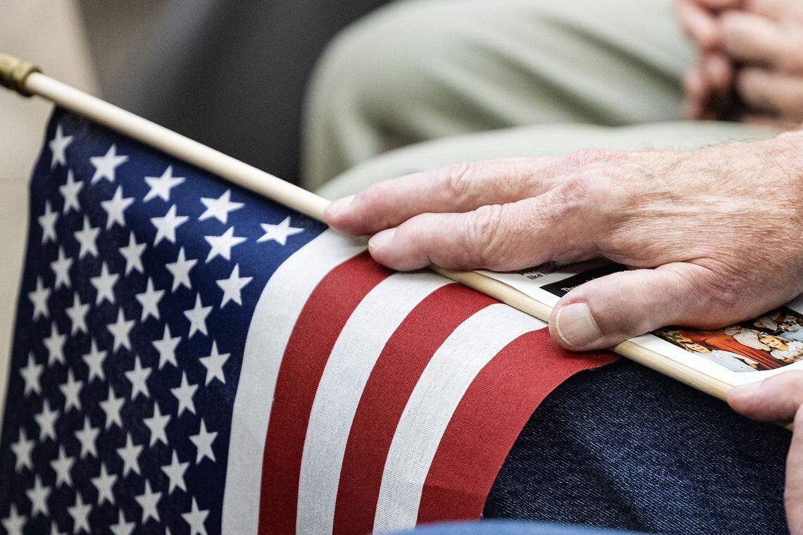 A protester holds the American flag while seated for the Keller city council meeting where they will discuss Item 287g on the council meeting agenda which is a resolution for the city to join forces with ICE on Tuesday, Aug. 5, 2025.