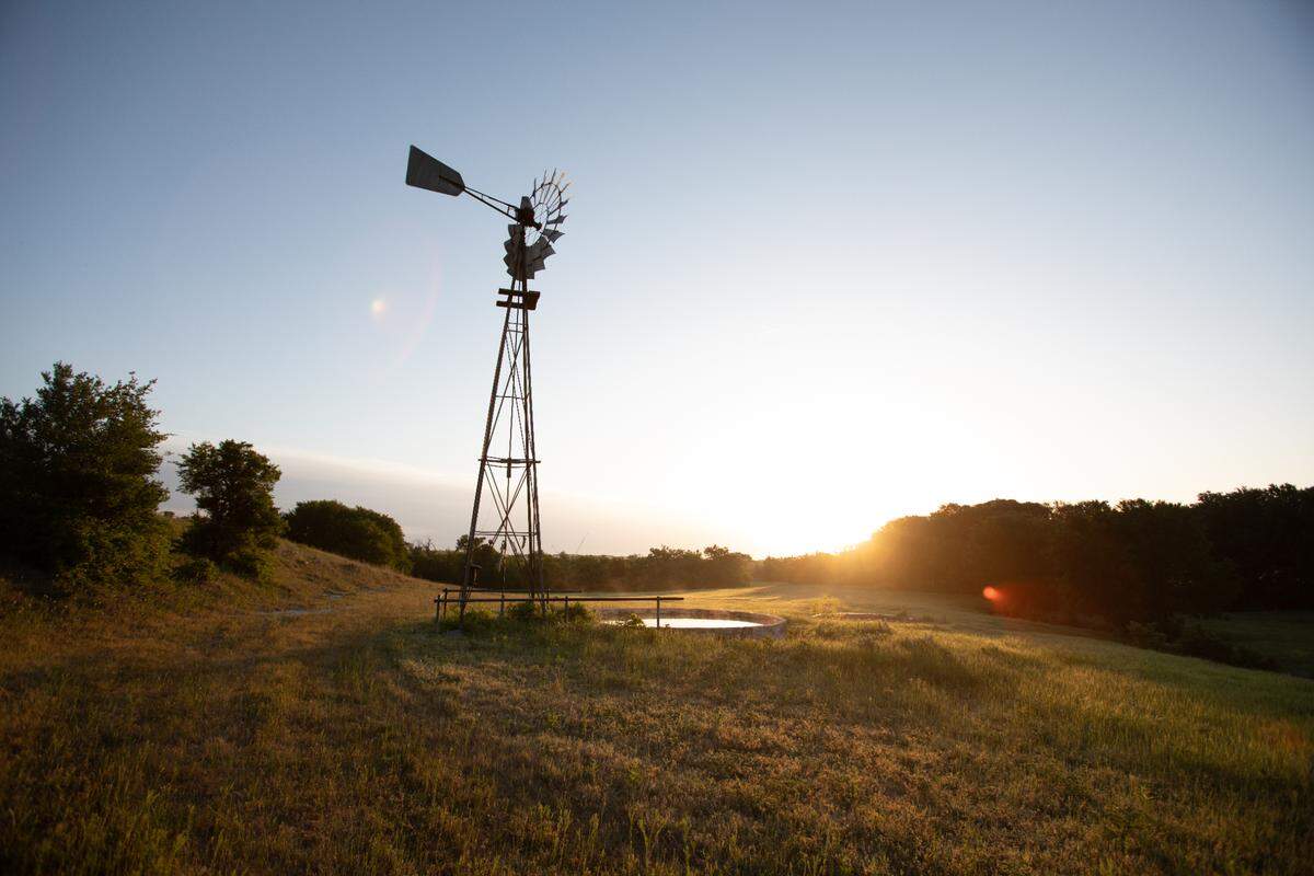 A windmill with a sunset in the background at the site of the new Maverick Golf and Ranch Club community.