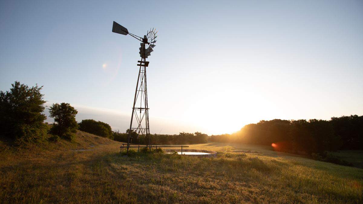 A windmill with a sunset in the background at the site of the new Maverick Golf and Ranch Club community.