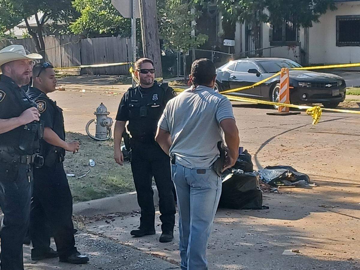 Fort Worth police investigate at the scene of Ross Avenue and NW 32nd Street, where officers shot and killed two armed men on Wednesday.