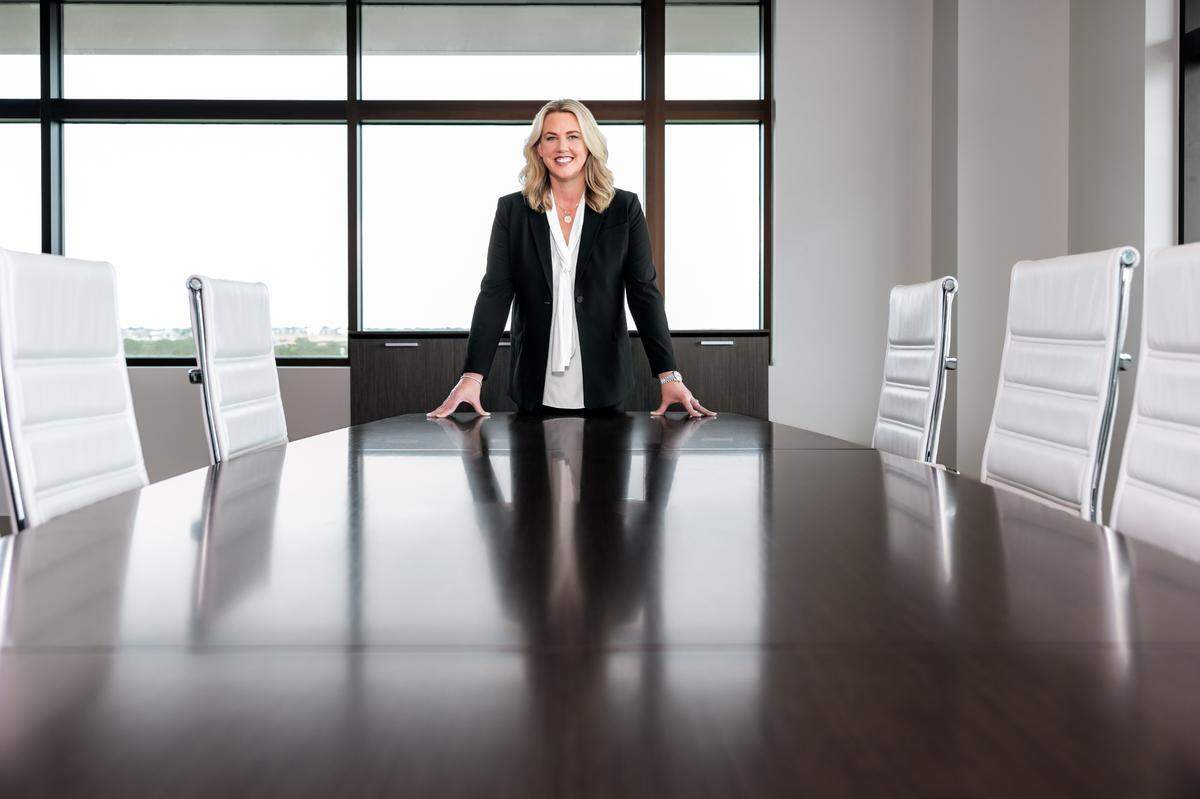 CEO of Bell Lisa Atherton stands at the end of a conference table.