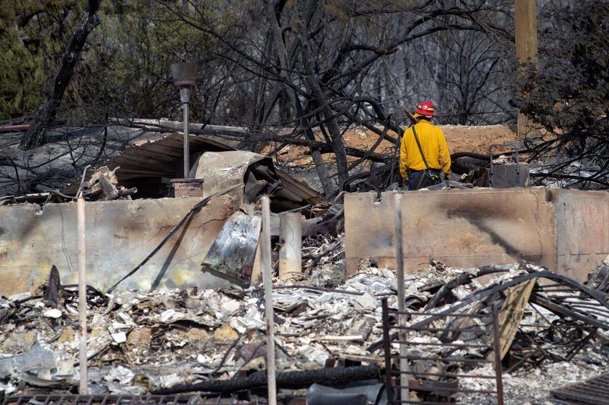 A firefighter observes the wreckage after a structure collapsed because of a wildfire on the coast of Possum Kingdom Lake in Graford, Texas, on Wednesday, July 20, 2022.