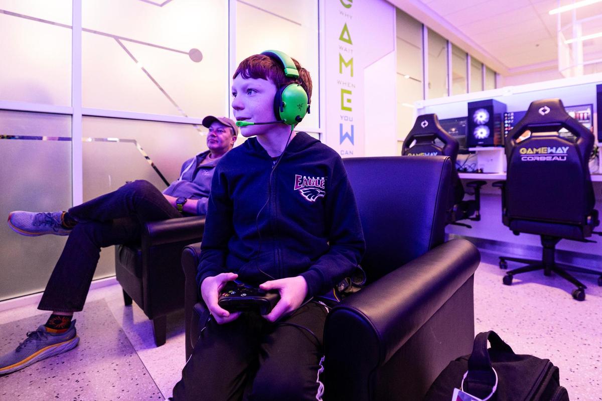Detroit resident James Killeen, 10, plays Minecraft on Xbox while his father Shaun watches during their flight layover at Gameway video game lounge in Terminal E at Dallas Fort Worth International Airport on Wednesday, March 26, 2025.