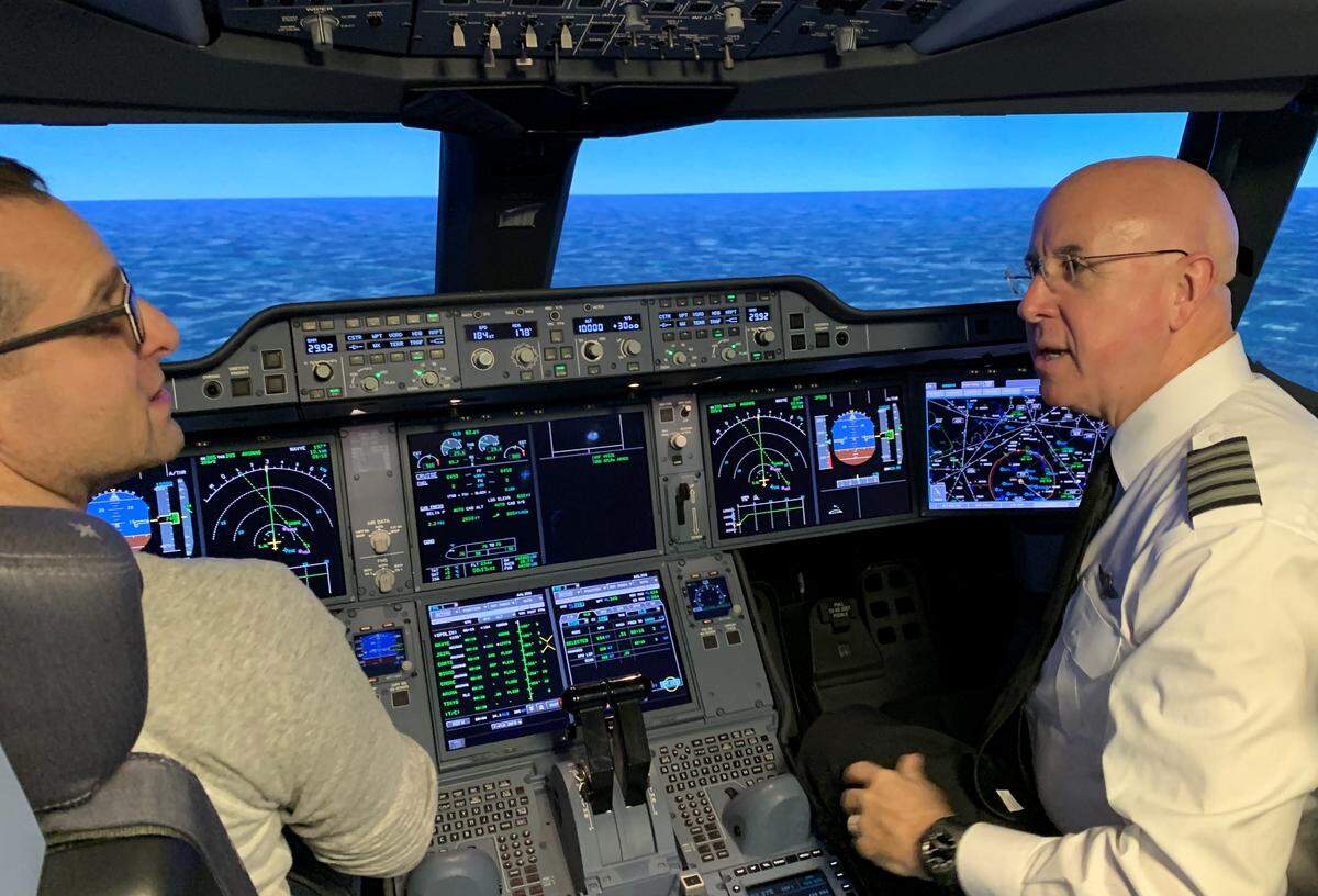 American Airlines Capt. John Dudley (right) explains an Airbus 350 simulator to a visitor at the company’s flight academy in Fort Worth.