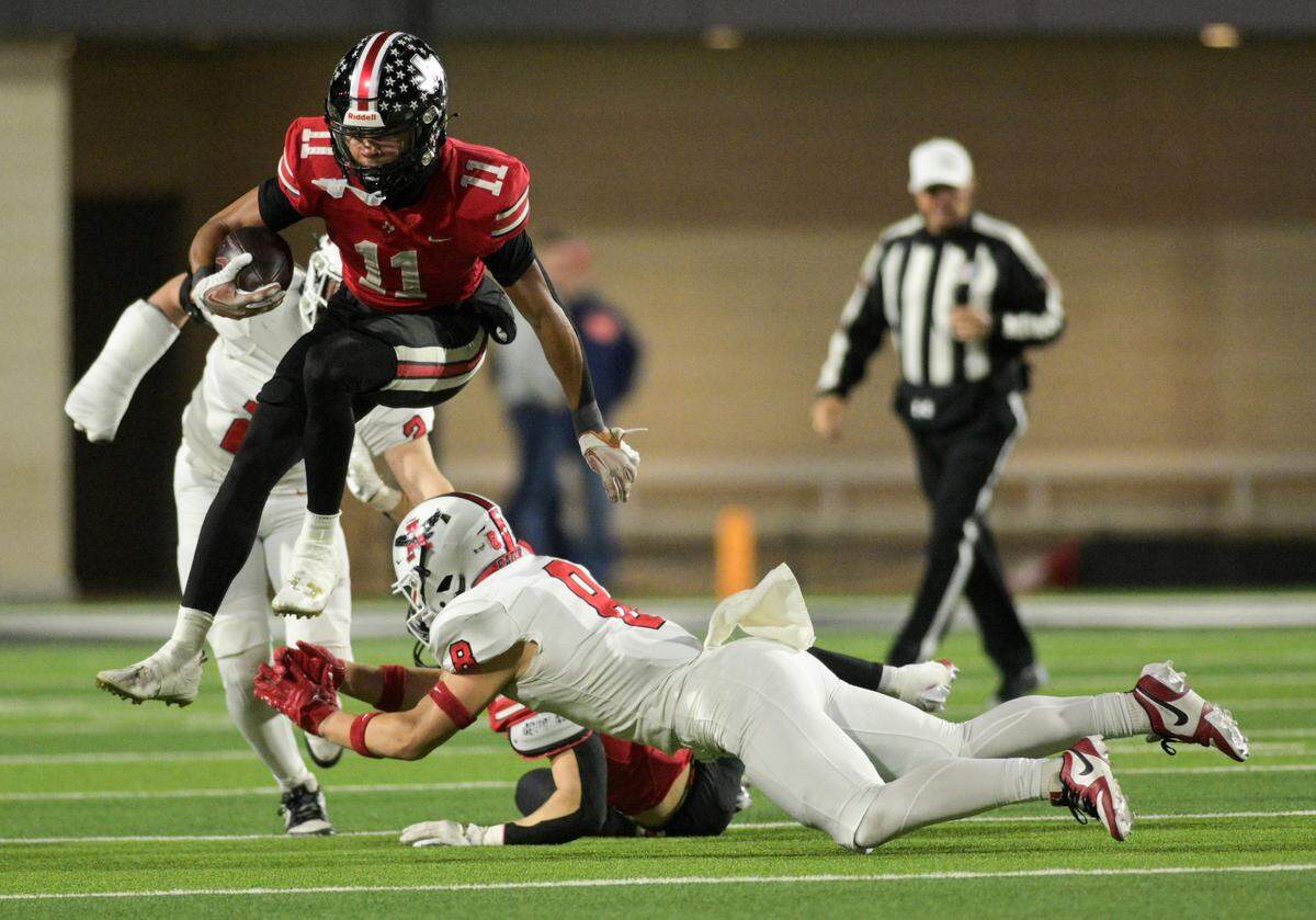 Lovejoy wide receiver Daylan McCutcheon (11) leaps over a tackle attempt from Argyle defensive back Nathaniel Bruce (8) during the Class 5A Division II Region I playoff game against Argyle High School at Prosper ISD Children’s Health Stadium in Prosper, Texas on Friday, Dec. 6, 2024.