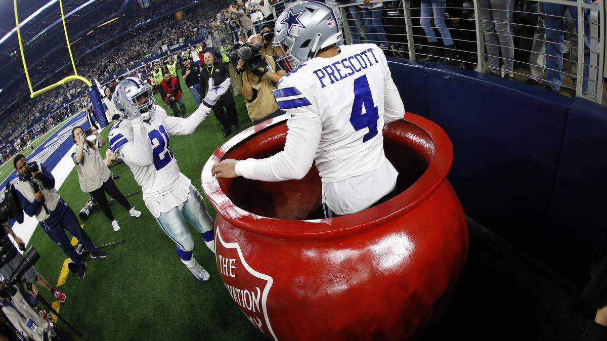 Dallas Cowboys quarterback Dak Prescott and running back Ezekiel Elliott celebrate a touchdown at a Salvation Army kettle during a Thanksgiving game in Arlington, Texas. Charities may have less to celebrate this year, if changes in federal tax law lead to a decrease in contributions.