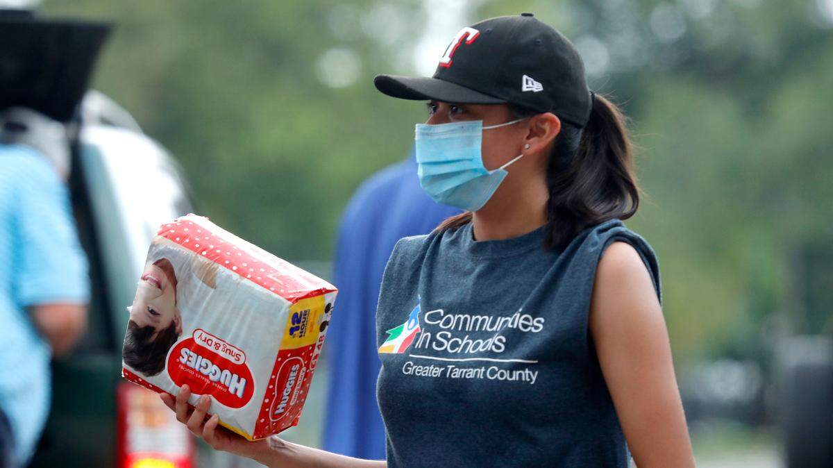 Melissa Flores hands out diapers during a drive through food pantry distribution by Catholic Charities during the coronavirus pandemic in Dallas, Thursday, July 2, 2020. (AP Photo/LM Otero)