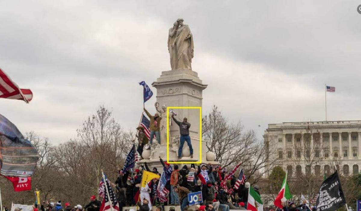 Philip Anderson, highlighted by a yellow box, speaks into a megaphone while standing ona statue at the Peace Circle on Jan. 6, 2021, according to the Justice Department.