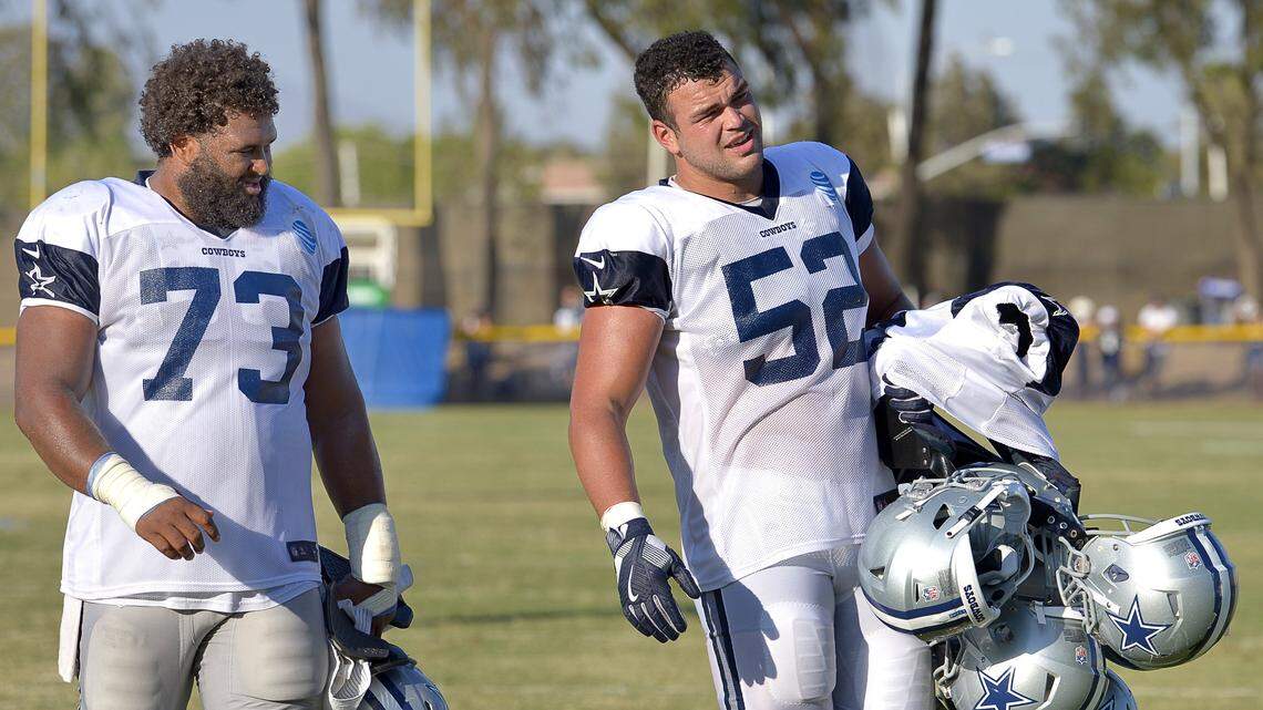 Dallas Cowboys center Joe Looney (73) watches as offensive guard Connor Williams (52) goes about his rookie duty of caring helmets of his teammates back to the locker room after practice at training camp in Oxnard, CA, Monday, Aug. 6, 2018.  