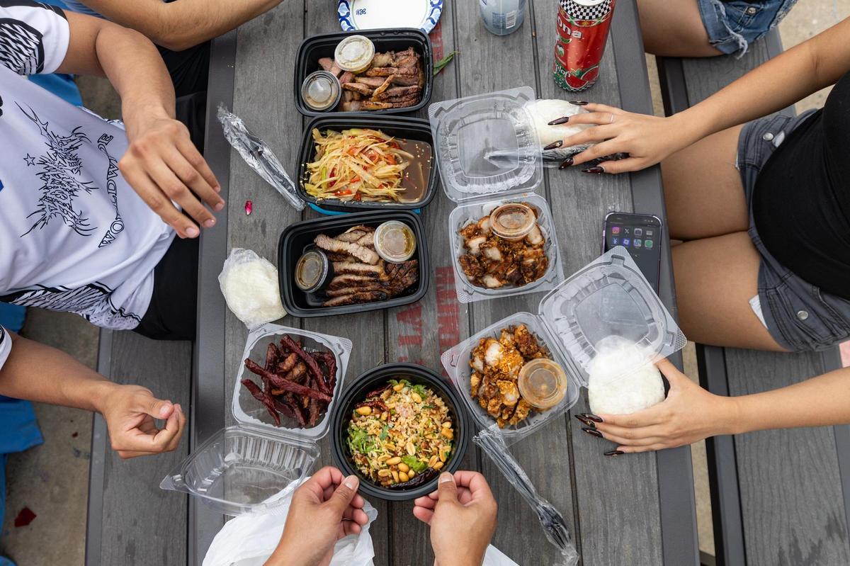 Festival attendees prepare to eat the papaya salad, Lao brisket, crispy pork belly, beef jerky, and fried rice from Asiannights Lao-Thai Cuisine on the third day of the Lao New Year festival at Wat Lao Thepnimith Temple in Saginaw on Sunday, April 27, 2025.