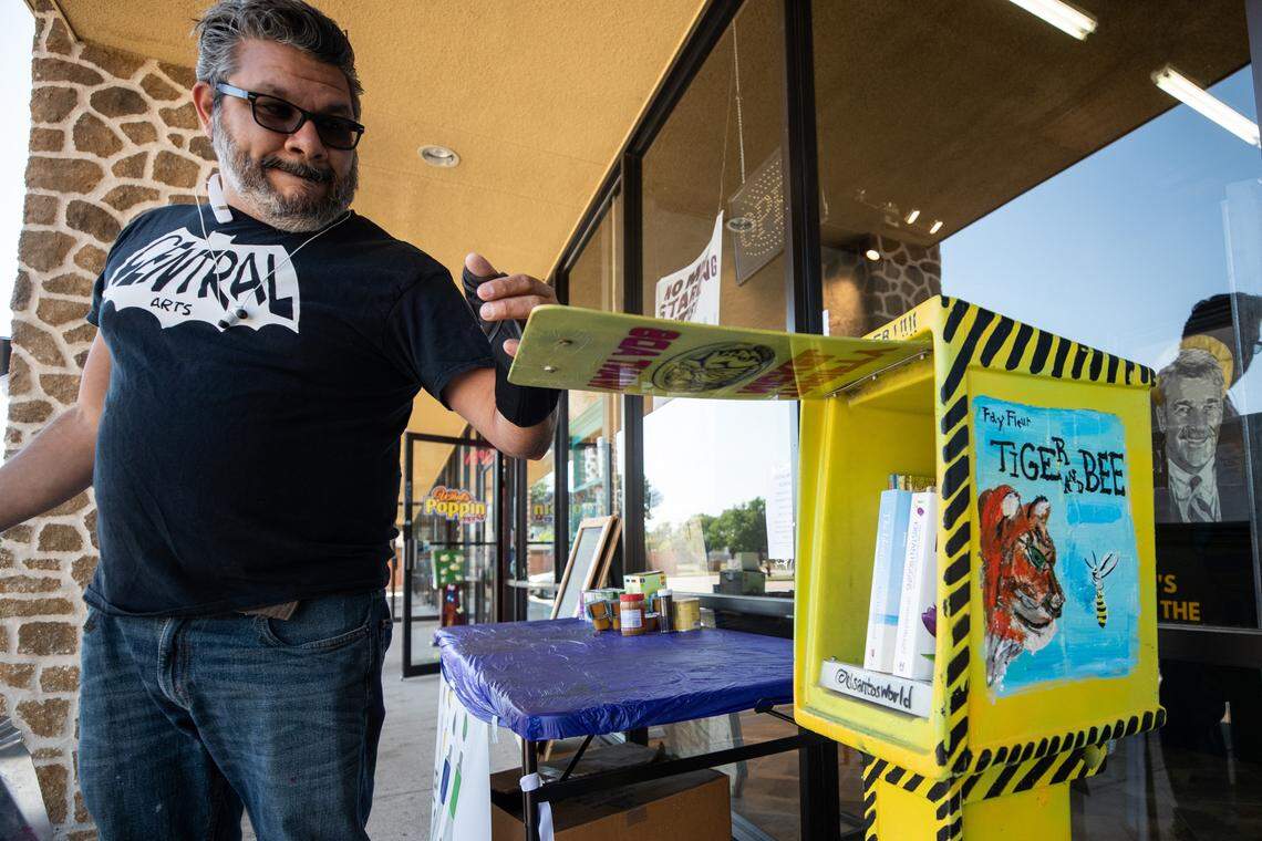 Josh Santillan checks on a tiny library outside his shop to provide books and art projects amid the coronavirus outbreak.