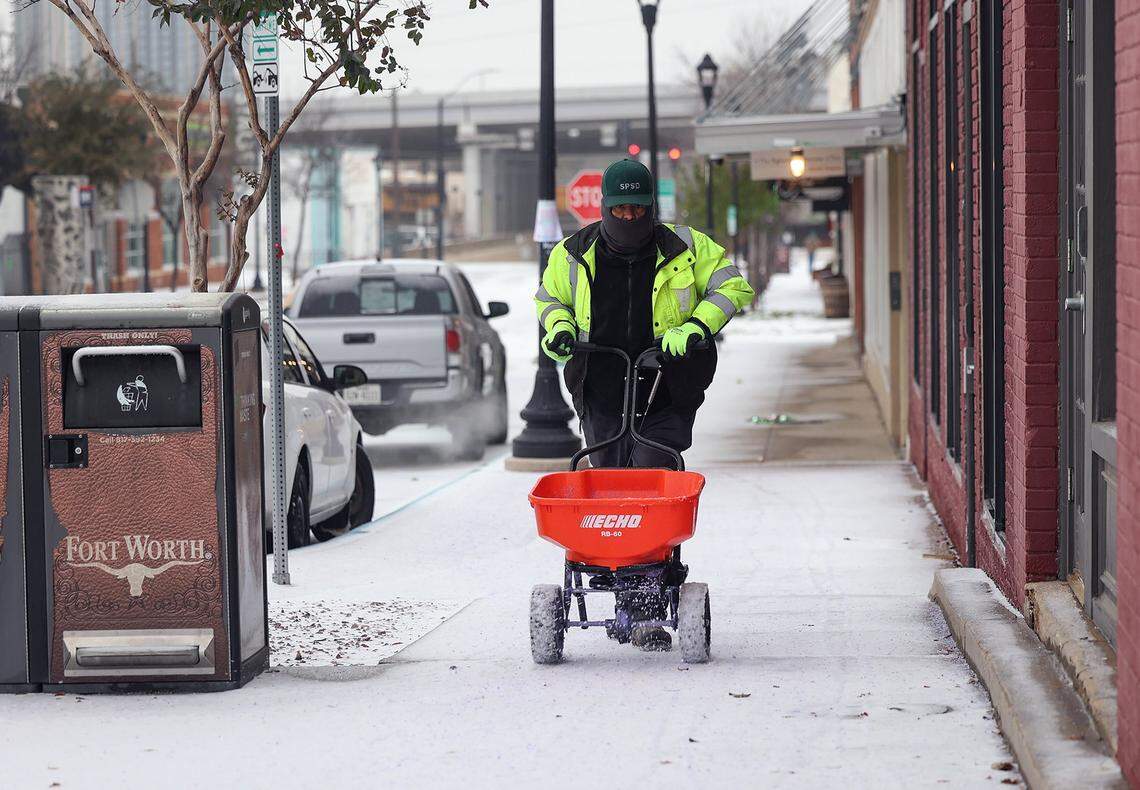 Antonio Alonso with SPSD Landscaping salts the sidewalks outside businesses on South Main Street near downtown Fort Worth on Saturday morning, Jan. 24, 2026. A massive Arctic cold front is moving across North Texas, causing freezing temperatures.