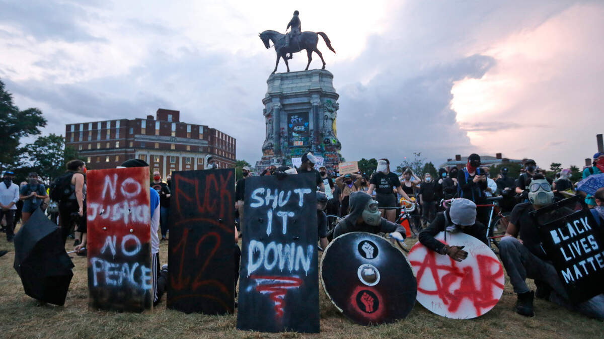 Protesters with shields and gas masks wait for police action as they surround the statue of Confederate Gen. Robert E. Lee on Monument Avenue, Tuesday June 23, 2020, in Richmond, Va. The state has ordered the area around the statue closed from sunset to sunrise. (AP Photo/Steve Helber)