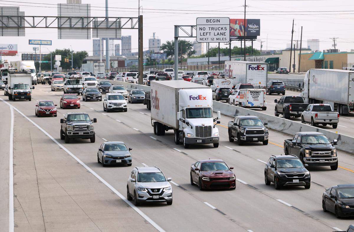 Semi-trucks and passenger vehicles on a busy highway, driving left to right.