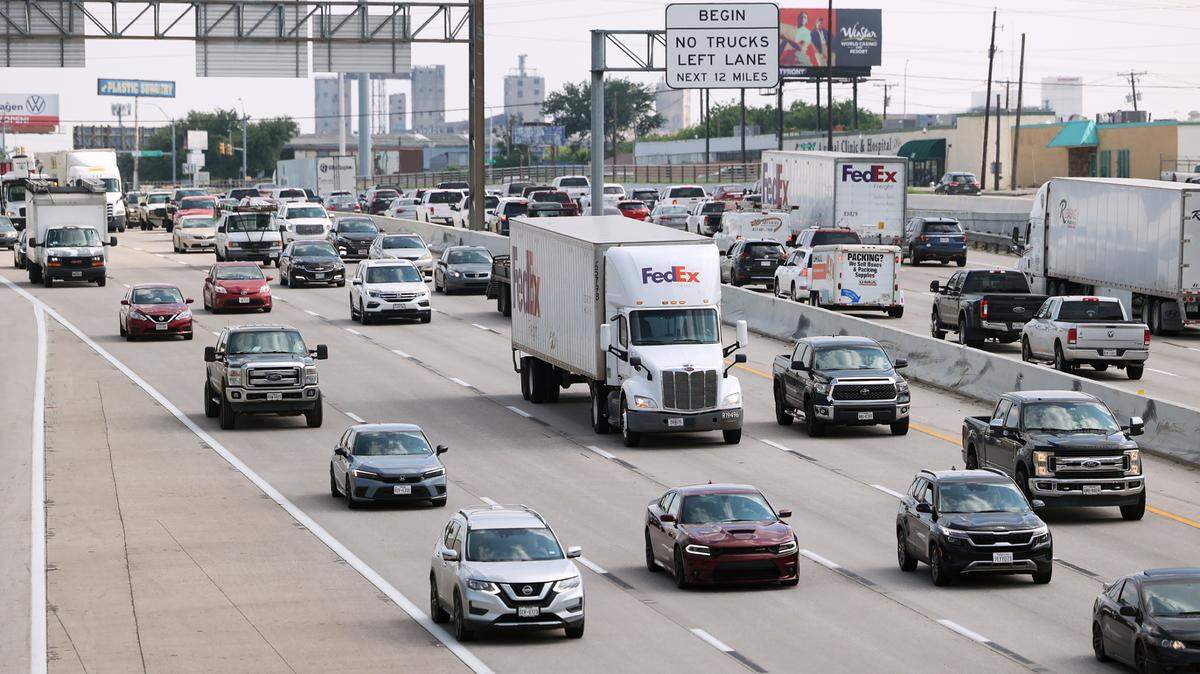 Semi-trucks and passenger vehicles on a busy highway, driving left to right.