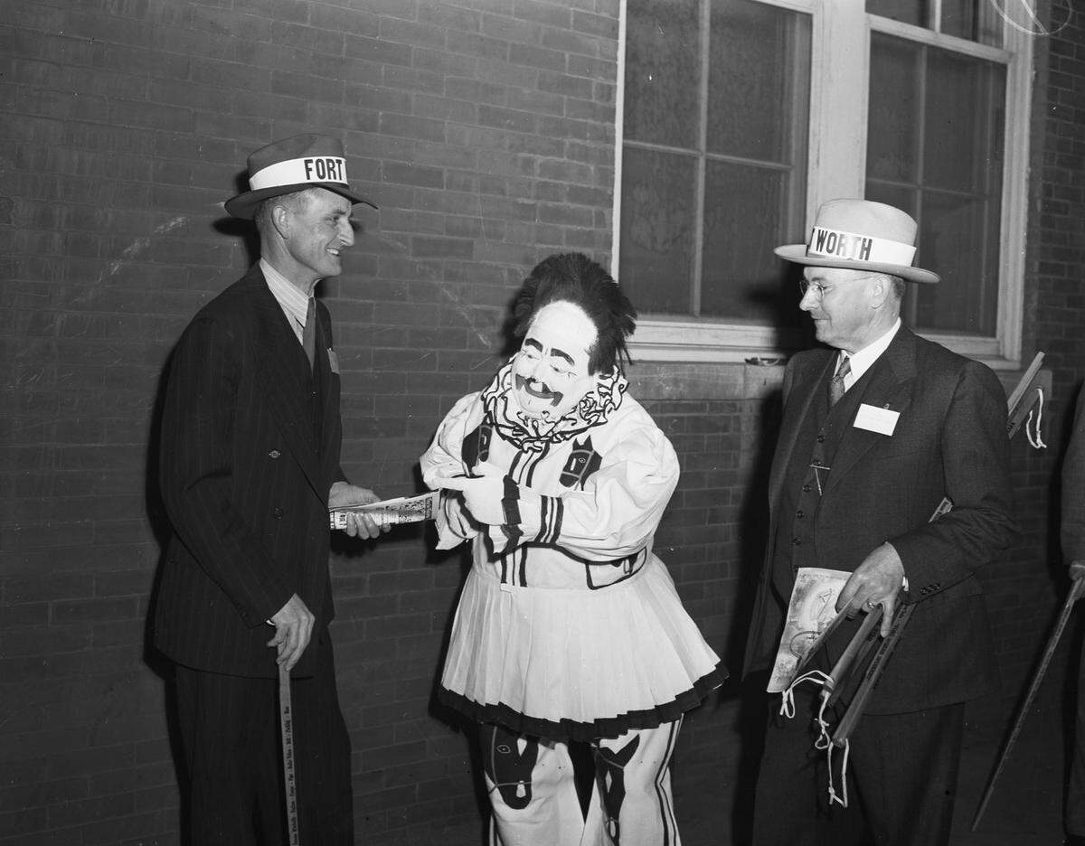 Two men wearing hats that say "Fort Worth" stand on either side of a plump clown