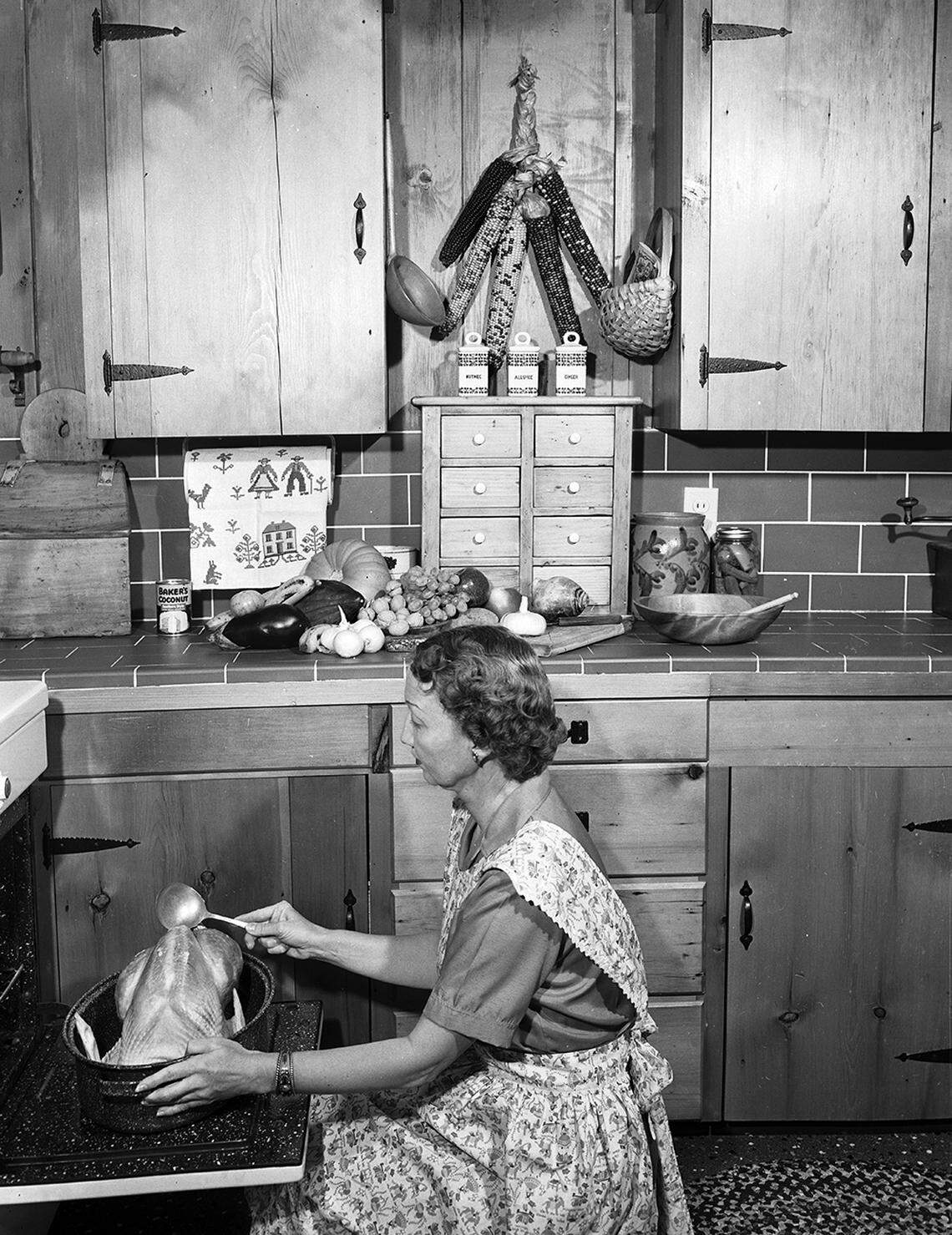 Nov. 1, 1952: From a society series on Thanksgiving table settings. The Country Kitchen: Before the dinner may be eaten, it must be prepared. Here, Mrs. Elbert W. Gunn, 3425 Worth Hills Drive, prepares “the noble bird.”