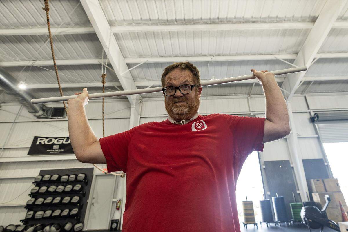 Kevin Kirkland attempts to lift a pipe over his head, his face is visibly straining with the effort.