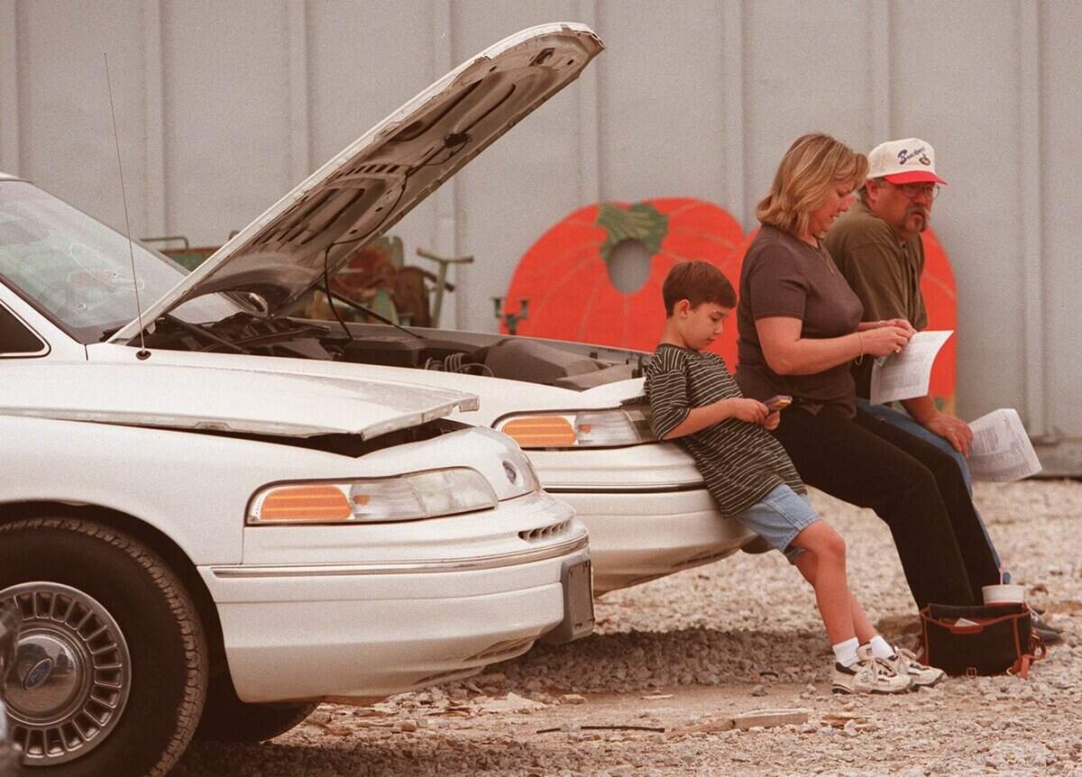 Feb. 27, 1999: Pat and Jenne Collins, with 9-year-old Travis, take a break on the bumper of a car for sale during a Southlake auction of surplus city vehicles and items seized by the police.