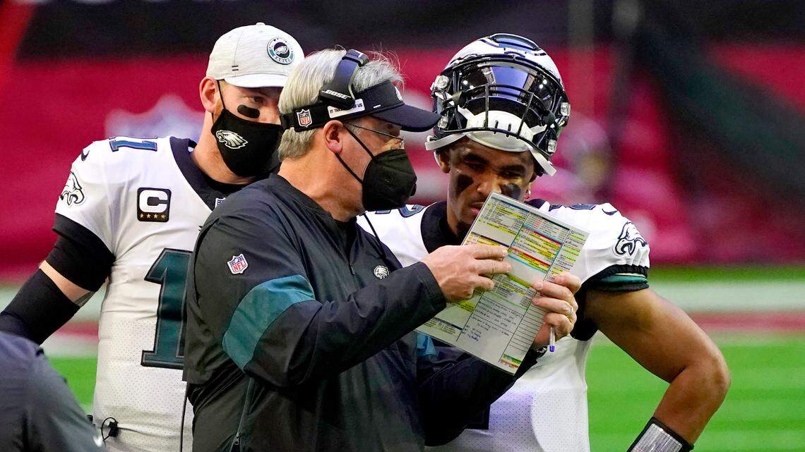 Philadelphia Eagles head coach Doug Pederson talks with starting quarterback Jalen Hurts as quarterback Carson Wentz (11) looks on during the first half of an NFL football game, Sunday, Dec. 20, 2020, in Glendale, Ariz.