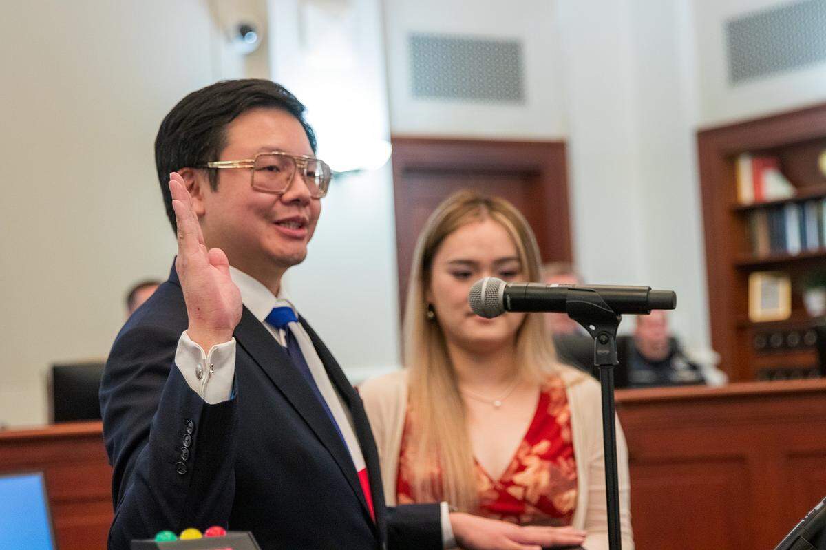 New council member Eric Wang takes the oath of office with his wife holding the Bible at the May 5 Southlake City Council meeting.