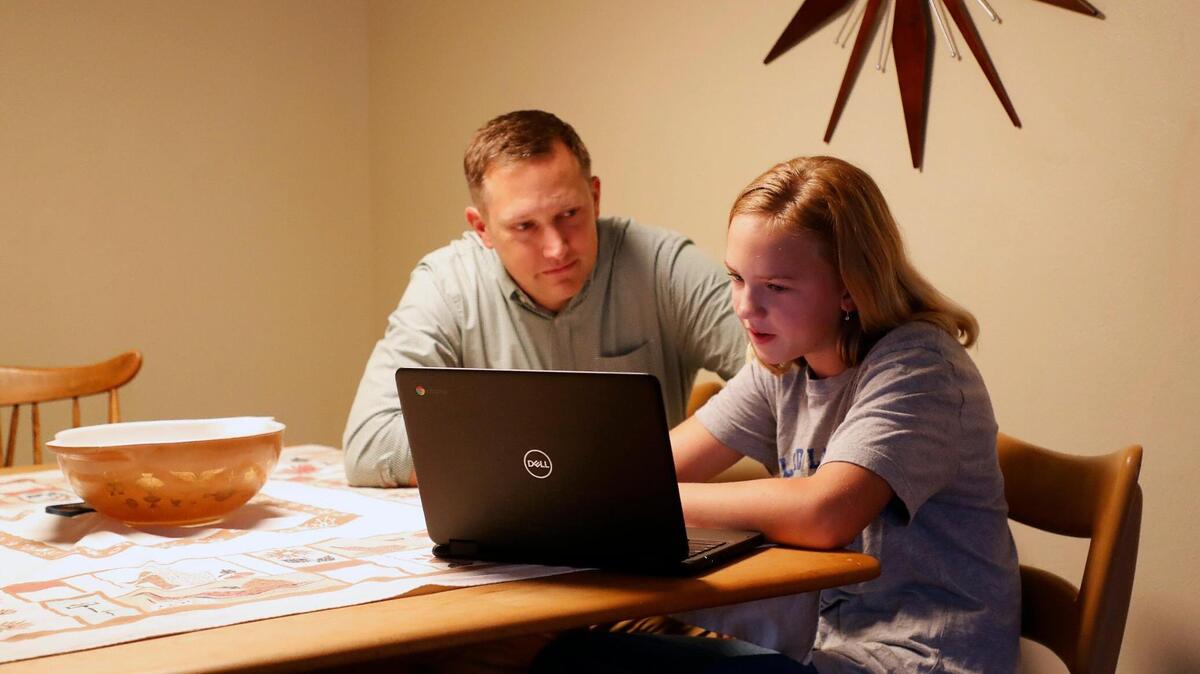 Russ Boyd works with his sixth-grade daughter, Bell, 11, on her homework. Bell, an Applied Learning Academy student, had to quarantine last month after being exposed to COVID-19.
