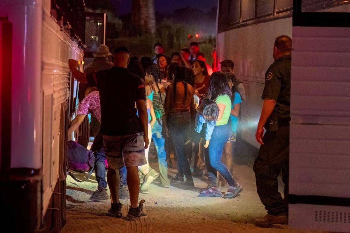 Border Patrol agents escort migrants onto a bus to be taken to a processing facility to begin their asylum-seeking process in Eagle Pass, Texas on June 25, 2023. Texas Governor Greg Abbott signed six bills aimed towards enhancing border security along the southern border. Of the six bills, one aims to install floating barriers in the middle of the Rio Grande in an attempt to deter migrants from illegally crossing into the United States. The initiative will begin in Eagle Pass and is projected to be fully installed by July, 2023. (Photo by SUZANNE CORDEIRO / AFP) (Photo by SUZANNE CORDEIRO/AFP via Getty Images)