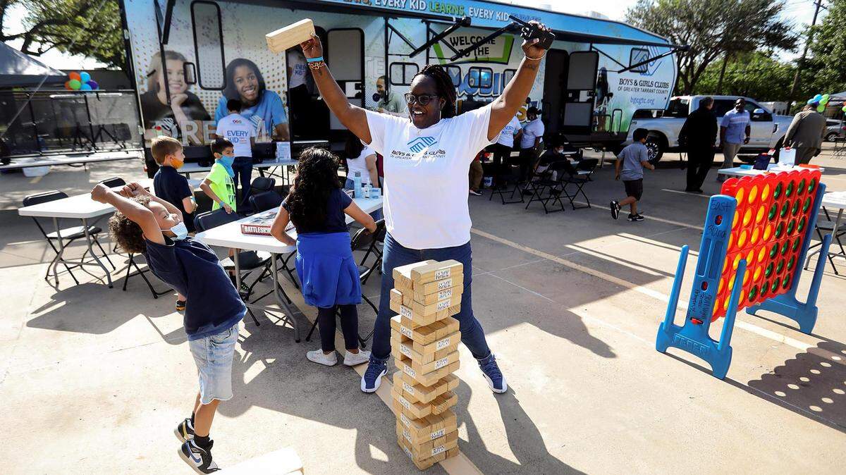 Shakia Jackson-Williams, assistant manager of the East Side Boys & Girls Club, celebrates a successful pull of a giant Jenga block with Boys & Girls Club member Aiden, 7, during the grand unveiling of the new Mobile Clubhouse Experience on Thursday, May 20, 2021, in Fort Worth. The Mobile Clubhouse is composed of a fleet of vehicles, including the flagship RV, that can be unpacked to bring services, as seen, directly to communities.