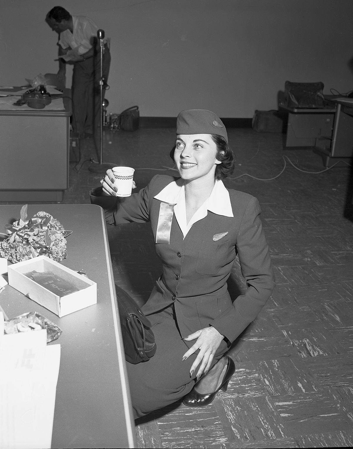 April 26, 1953: A Braniff International Airway hostess, Jean Vickrey of Dallas, smiles while drinking coffee during the grand opening of the Greater Fort Worth International Airport.