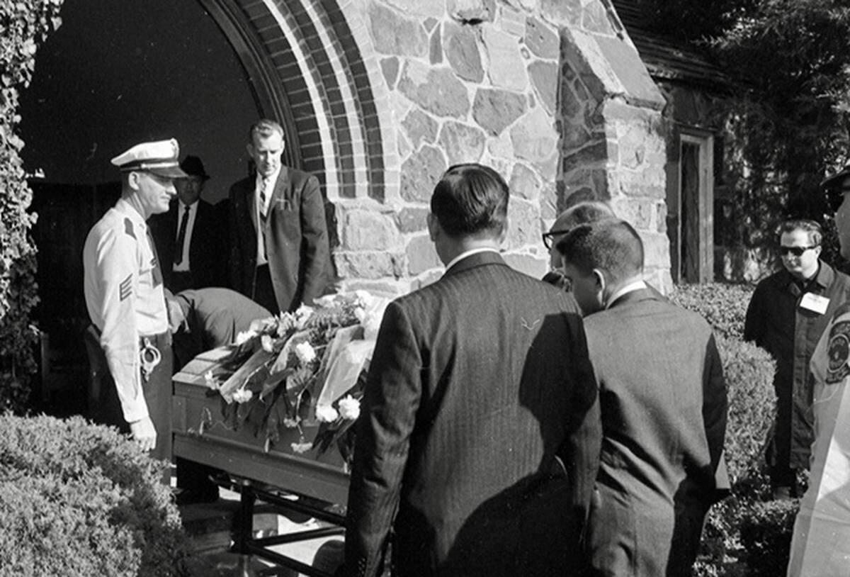 Pallbearers made up of newsmen and police bring out Lee Harvey Oswald’s casket from the chapel at Rose HIll Cemetery, Fort Worth, for burial, 11/25/1963. The person at right may be radio music host Mark Stevens of KFJZ/1270 AM.