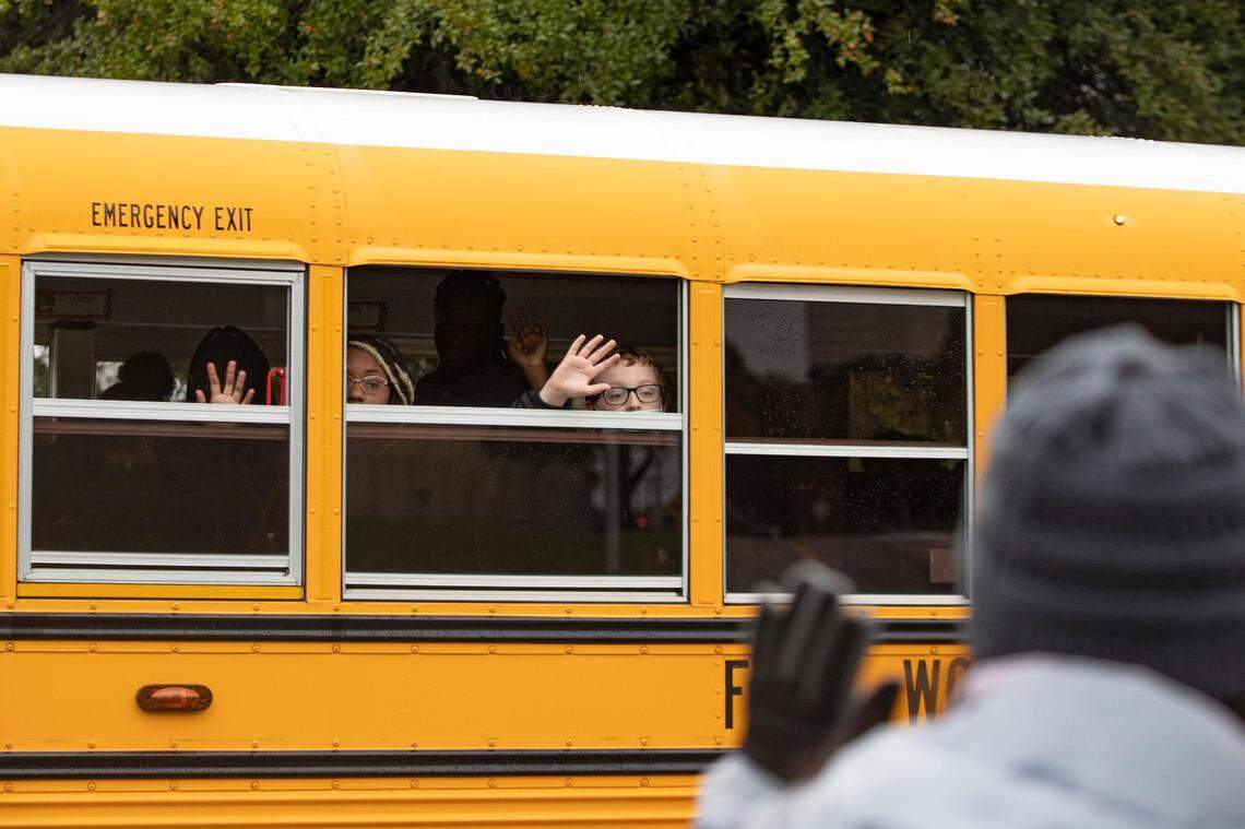 Fort Worth ISD students wave from a school bus during the Veterans Day Parade winding through Fort Worth on Friday, Nov. 11, 2022. Despite rain, hundreds of participants marched down North Forest Park Boulevard, waving American flags and signing a medley of military songs.